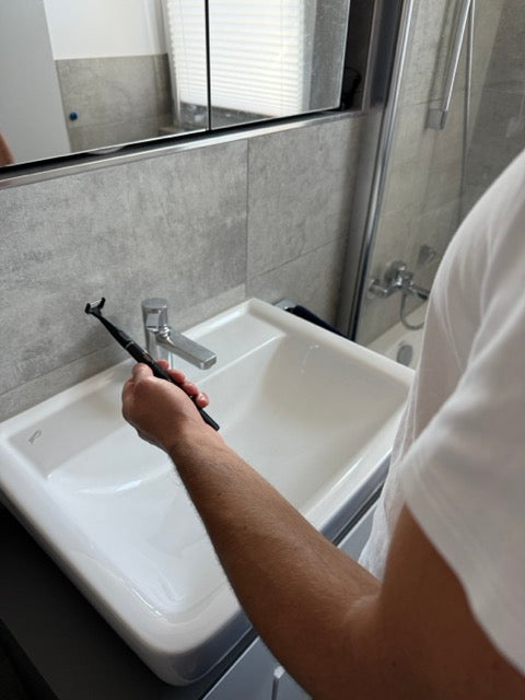 Männlicher Kunde testet den esaflosser One im Badezimmer – elektrische Zahnseide für gründliche Zahnzwischenraumreinigung