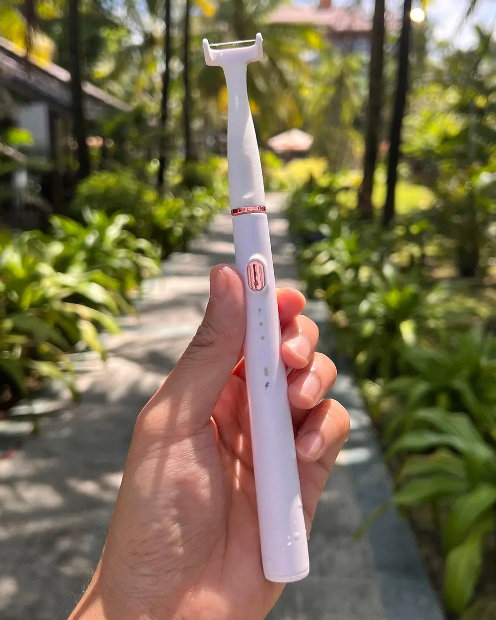 Weibliche Kundin ist auf Reisen und hält den esaflosser von esavea zwischen Palmen. Der Ideale Zahnzwischenraumreiniger für Reisen.