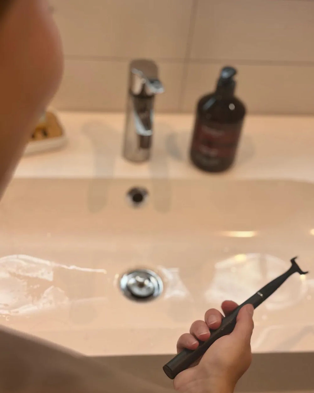 Weibliche Kundin testet den esaflosser One im Badezimmer bei ihrer täglichen Routine – elektrische Zahnseide für gründliche Zahnzwischenraumreinigung